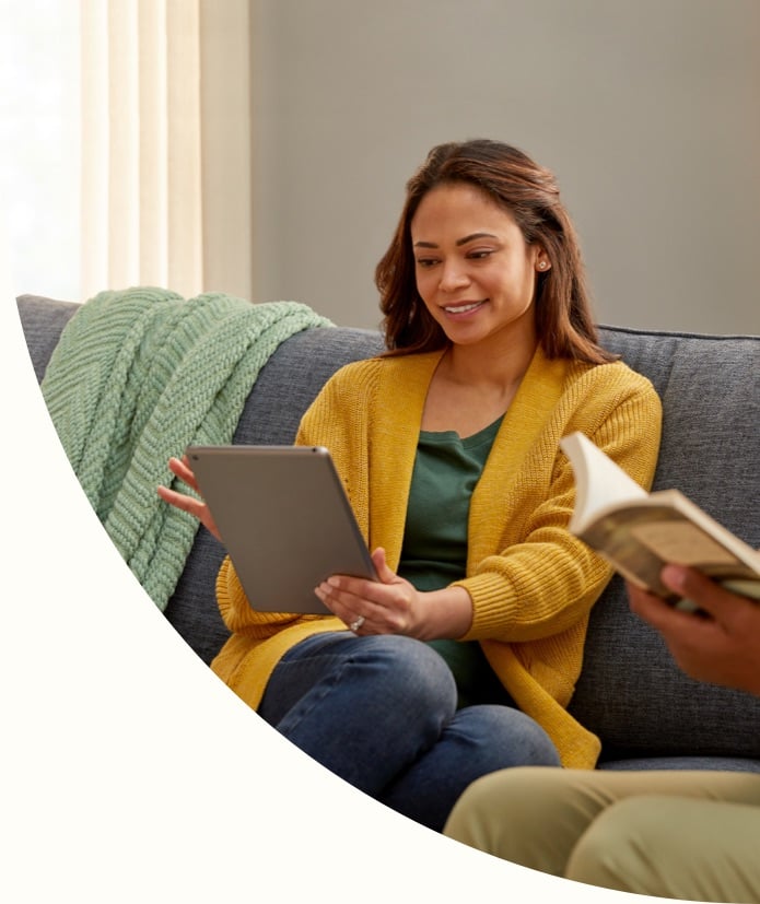 shot of a couple on a couch using a tablet and reading a book