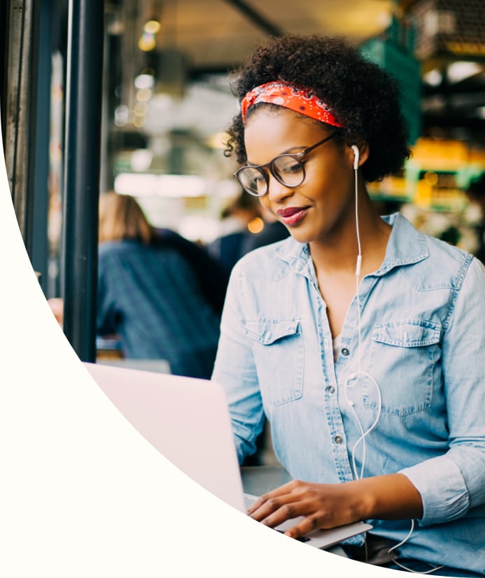 Focused young African woman sitting alone at a counter in a cafe working on a laptop