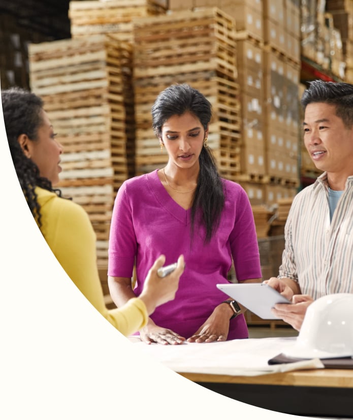 a male and two females having a meeting in a warehouse using a tablet