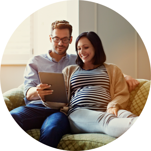 pregnant woman and her husband sitting on their sofa using a digital tablet